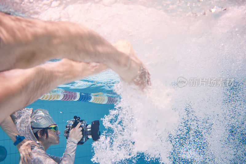 水下摄影师在游泳池中拍摄男性游泳者