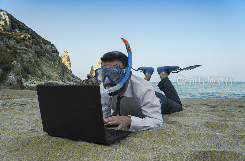 带着通气管的商人在海滩上使用电脑