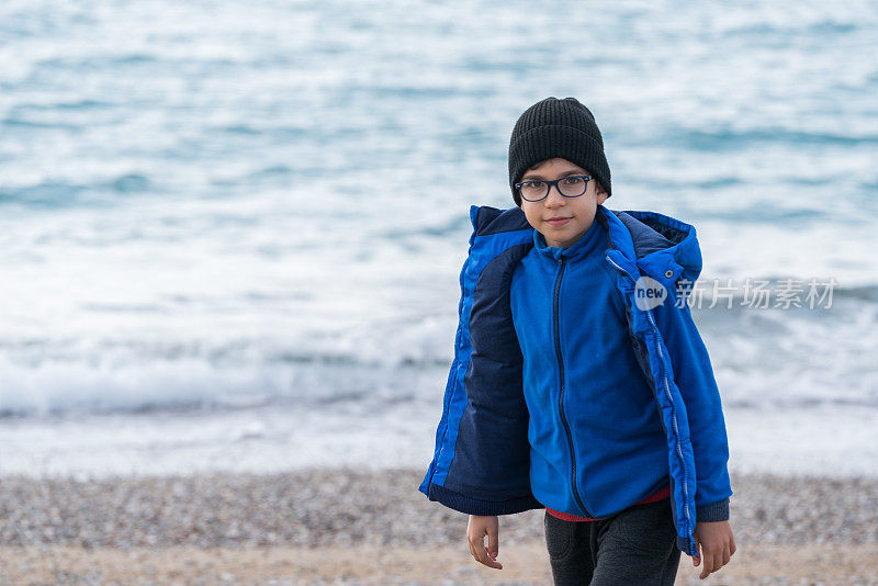 快乐的男孩在一个冬日的海滩上散步