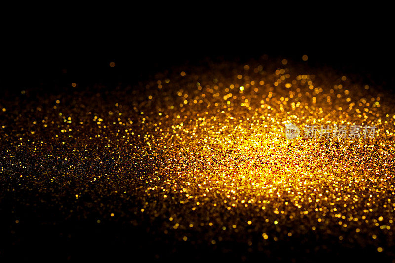 在有拷贝空间的黑色背景上撒上金色的闪光粉。