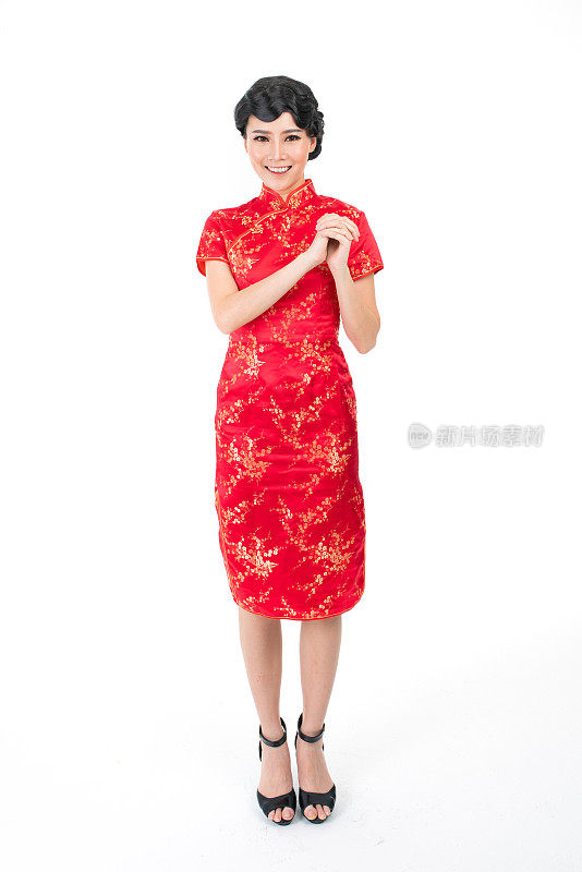 亚洲华人穿着中国传统服装旗袍，摆出中国新年问候的架势