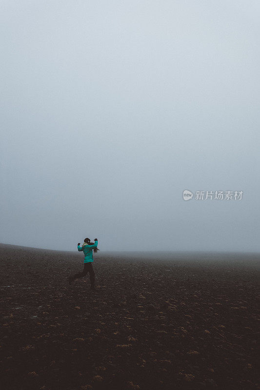 在冰岛，一个女人的剪影走过浓雾弥漫的火山景观