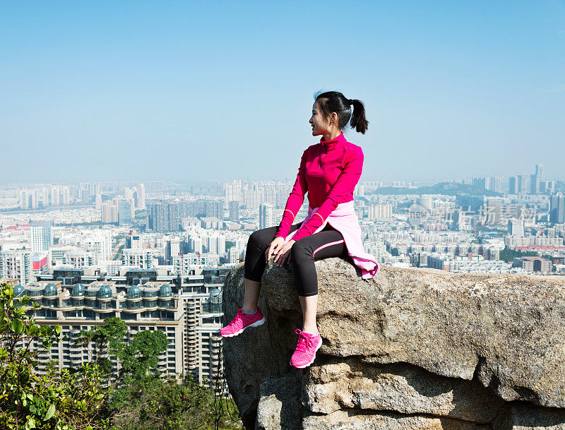 女人坐在山顶上欣赏风景