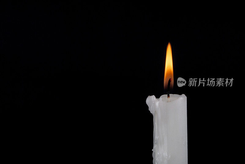 白色石蜡蜡烛燃烧和旧烛台孤立在黑色背景和文字空间