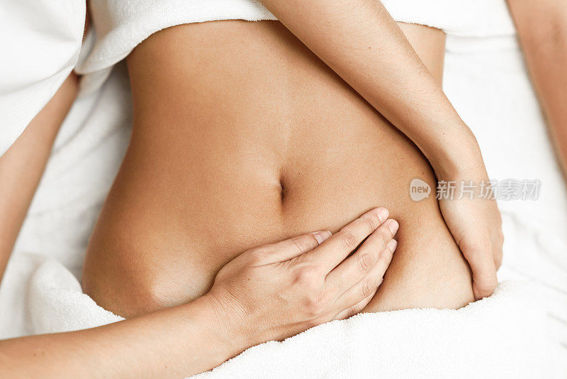 用手按摩女性腹部。治疗师在腹部施加压力。
