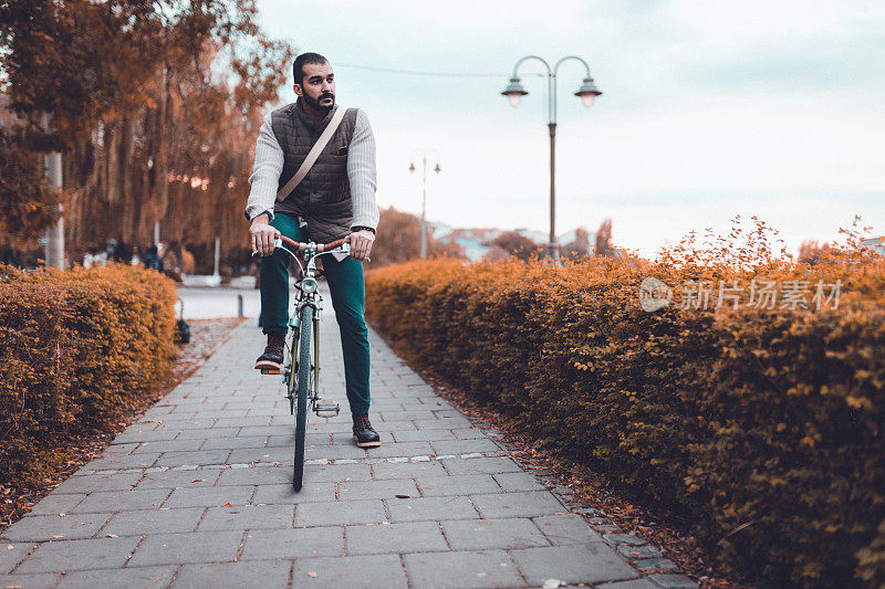 一个年轻人在阳光明媚的秋日骑着自行车去上班