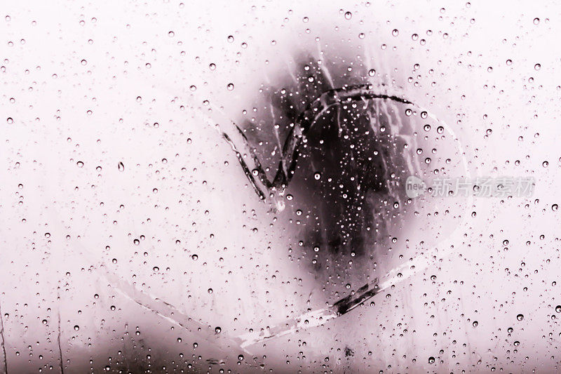 水滴的纹理顺着窗玻璃流下。雨滴落在汽车玻璃背景上，照片模糊，对焦柔和