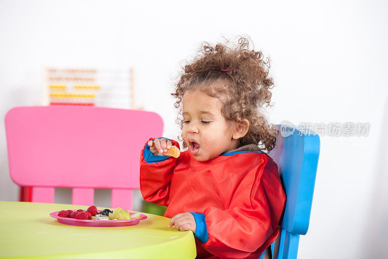 幼稚园里，小女孩在餐桌上吃水果