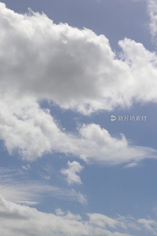 蓝色天空映衬着蓬松、缕缕白云的特写