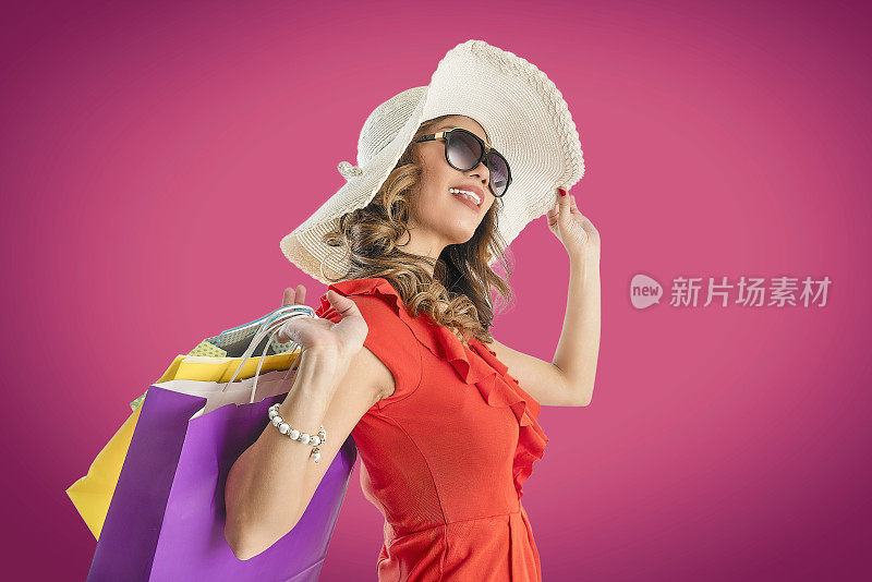 亚洲女人拿着花哨的购物袋在粉红色的拷贝空间