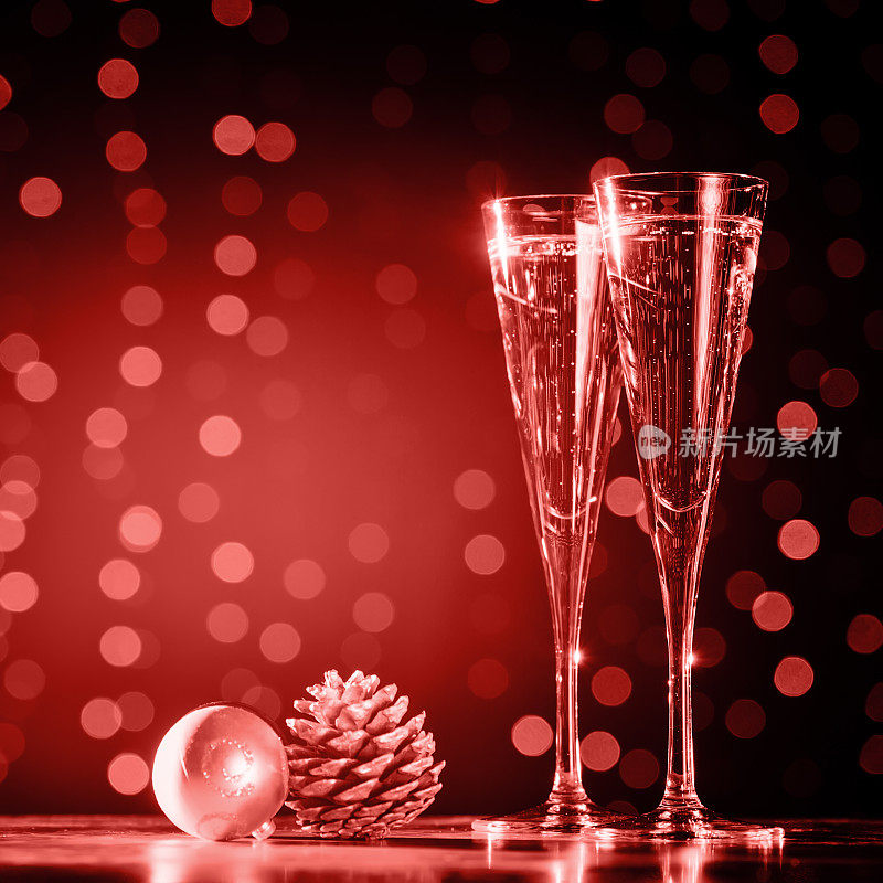两杯香槟和圣诞玩具。节日灯光散景背景。紫外光色调，2018年度流行色。活珊瑚主题——2019年度色彩