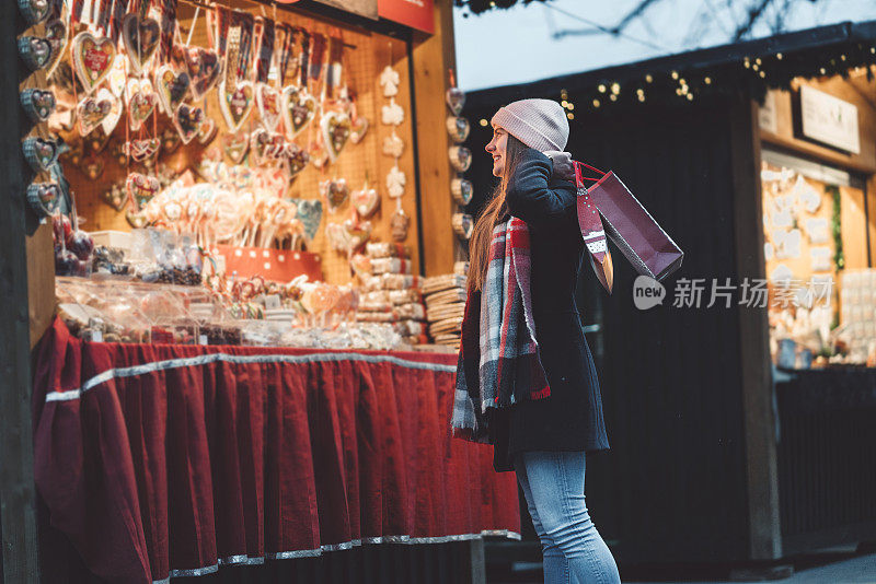 在圣诞市场-年轻的女人挑选礼物给她的家人