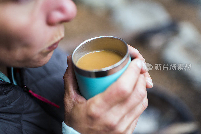 一个女人在露营地喝着她温暖的咖啡