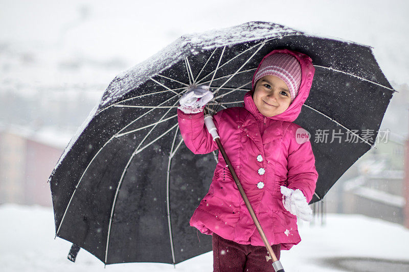 小女孩撑着伞在下雪