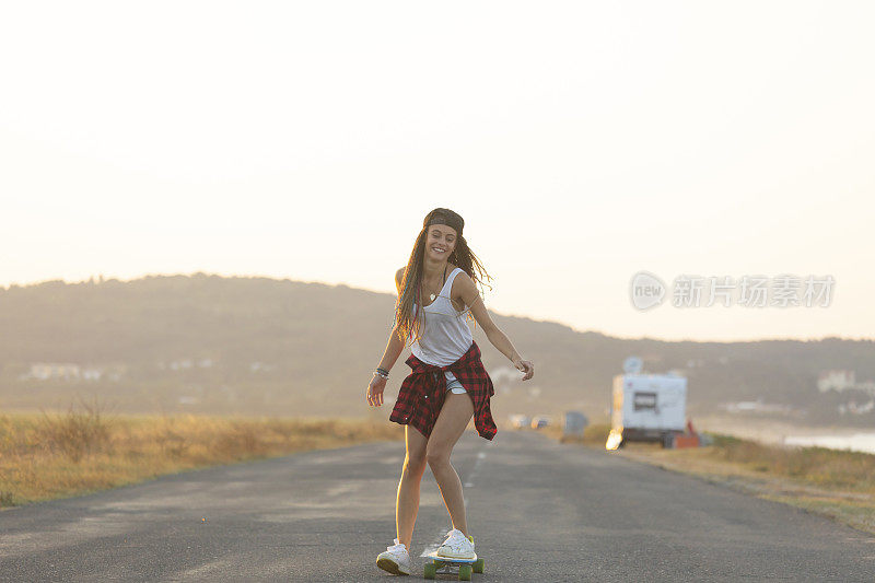 美丽的女孩带着长板在路上滑冰