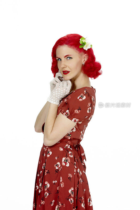 年轻的女人穿着复古的红衣服，红头发，站在白色的背景上