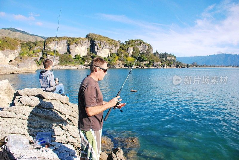 一个父亲和他的孩子在海岸岩石上钓鱼