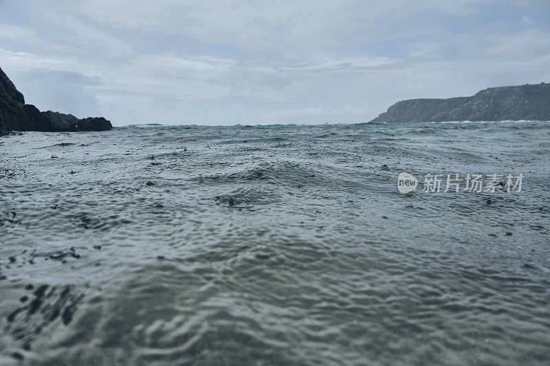 六月阴沉沉的一天，康沃尔的佩德旺德海滩海面上下着大雨。