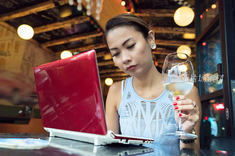 自由女工作与笔记本电脑和享受在酒吧喝酒