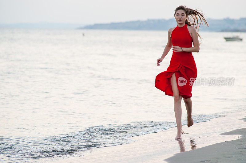 穿红衣服的年轻女子在海滩上跑步