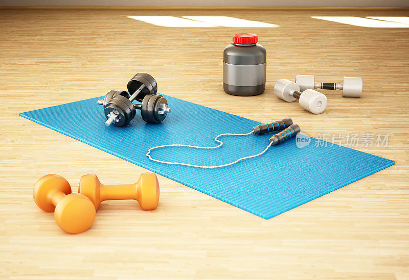 地板上放着普拉提垫、球、哑铃和其他健身器材
