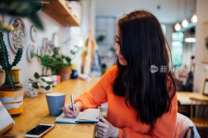 在咖啡馆做笔记的女人