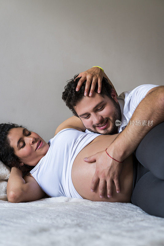 男人抚摸着妻子怀孕的腹部