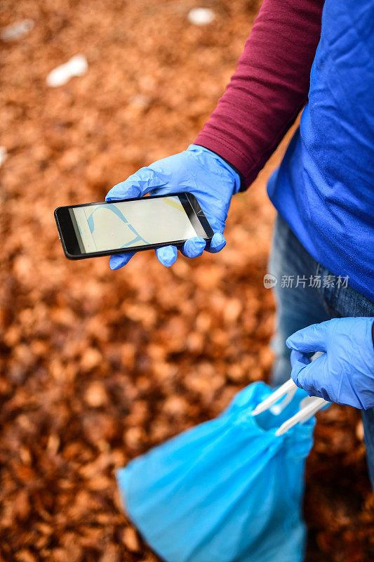 女性使用智能手机应用程序定位附近被扔的垃圾