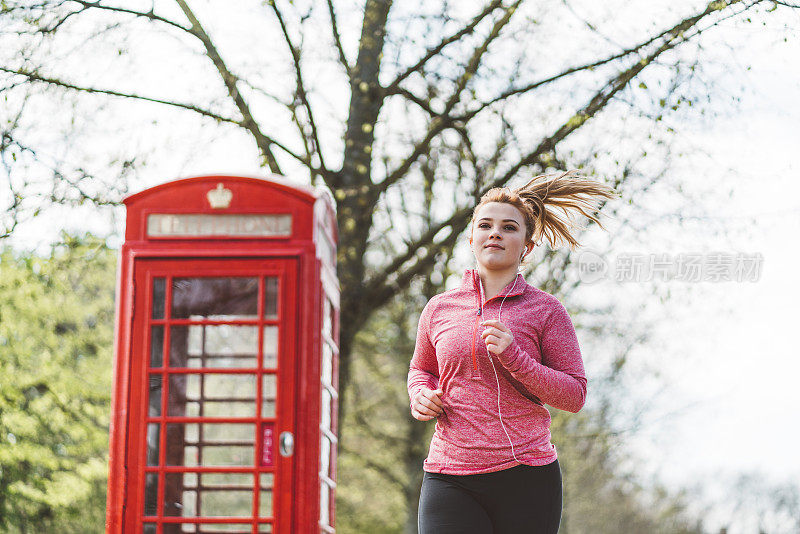 在伦敦一个红色电话亭旁跑步的女人