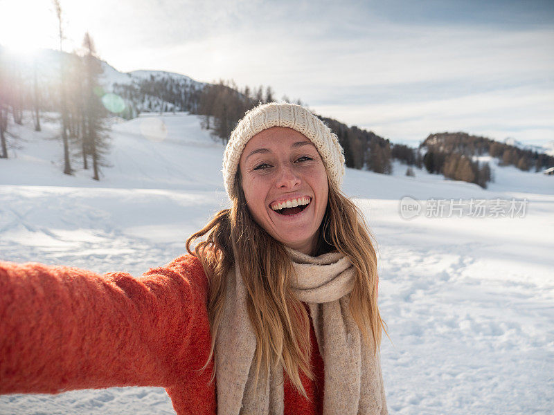 年轻女子在冬天与雪山景观自拍;人们在寒假里玩得很开心