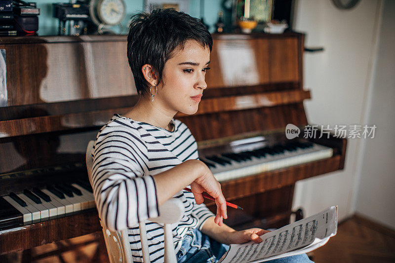 年轻的钢琴家在她家里的房间里写音符