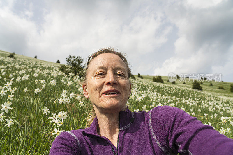 成熟的女人在水仙花草地上自拍