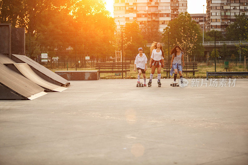 快乐的少女们在滑板公园里玩滑板和溜冰鞋