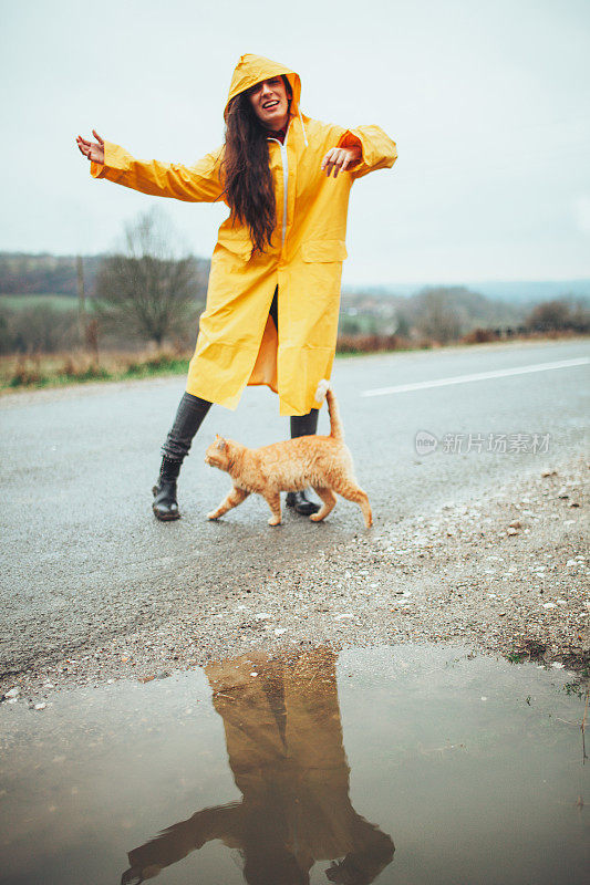 快乐的女孩和猫在大自然的雨