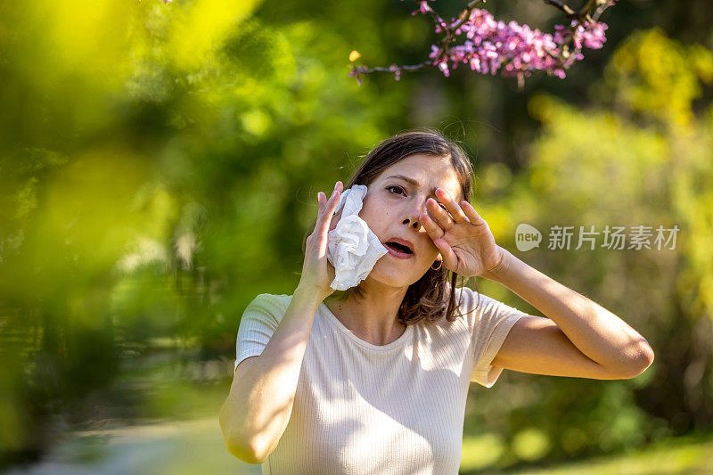 在鲜花盛开的花园里打喷嚏的女人