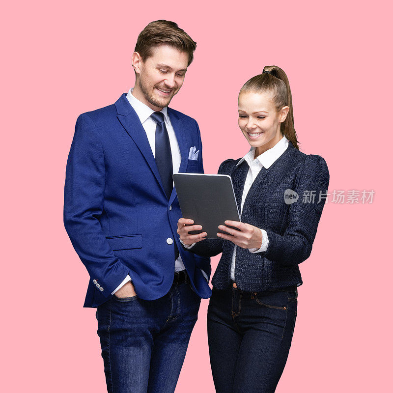 白人年轻男性女商人站在彩色背景下穿着运动夹克，使用数码平板电脑