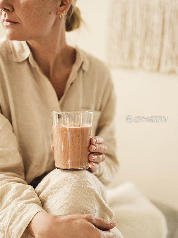 早上穿着亚麻睡衣喝健康奶昔的女人