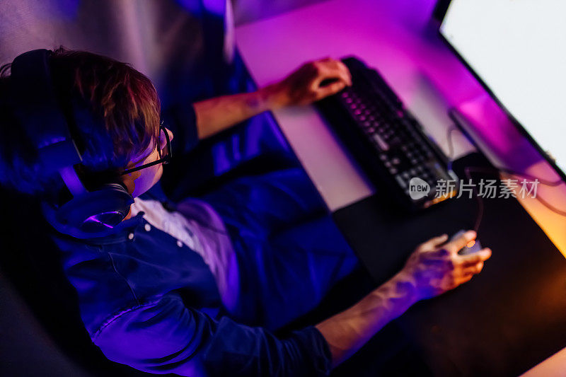 玩家坐在有霓虹灯的房间里，以个人电脑的第一人称玩在线视频游戏