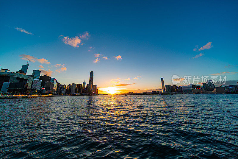 夕阳下的维多利亚港上空，可以看到香港市中心的摩天大楼。