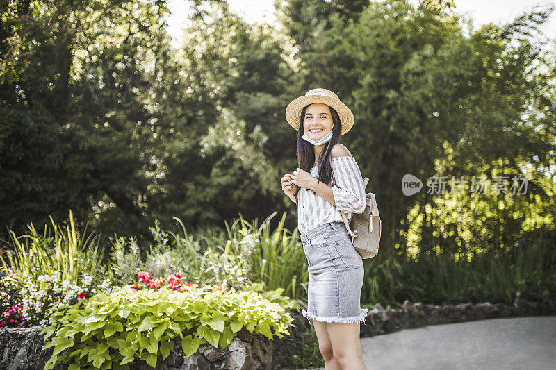 在冠状病毒大流行期间，戴着防护面罩的美丽女子在大自然中度过时光