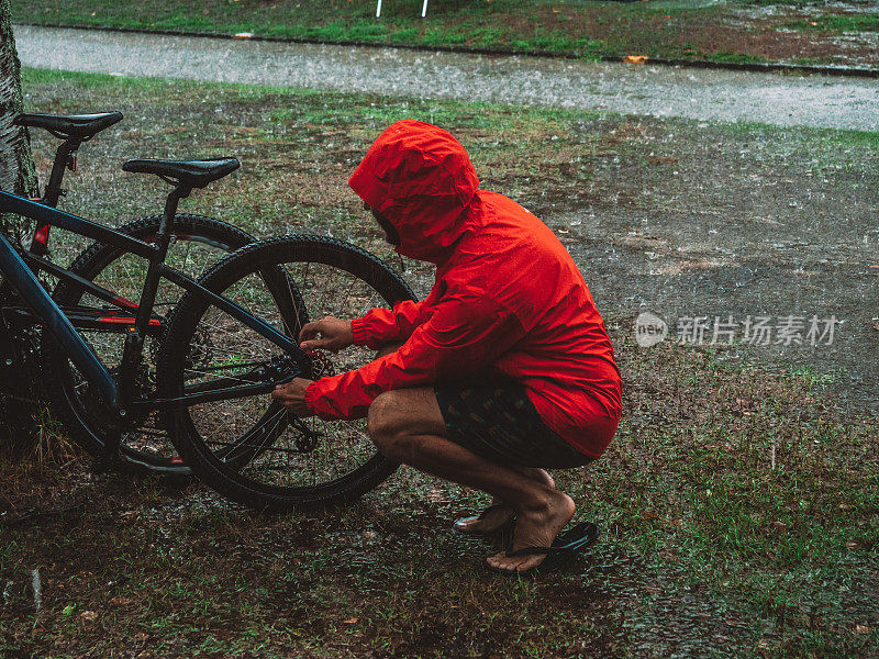 一名男子在暴雨中修理山地车