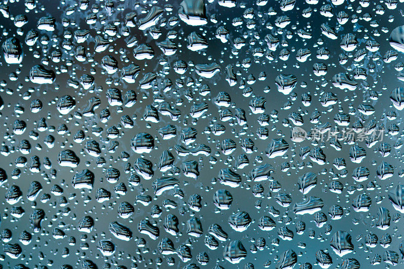 微距雨滴蒸气落在窗玻璃上。雨滴落在窗玻璃表面。透过窗户观看。雨滴落在玻璃上。水模式结构