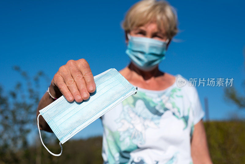 戴着防感染口罩的妇女给别人戴着防电晕口罩