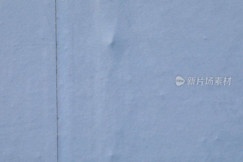 淡蓝色的纸张覆盖着不均匀的广告围板背景