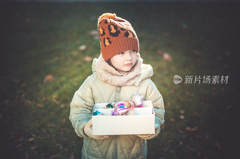 一个学龄前的小女孩手里拿着盒子里的圣诞装饰品