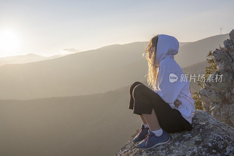 清晨，女徒步旅行者在阳光明媚的山脊上放松