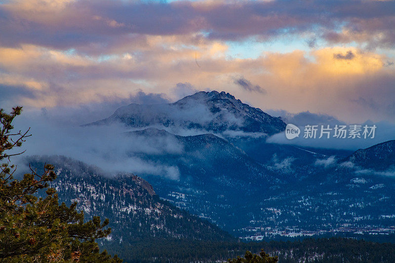 日落-树和雪与高海拔的山和天空的背景