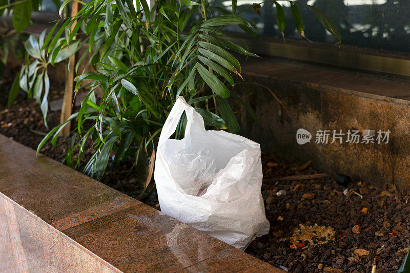 白色购物塑料袋用垃圾铺在花坛地面上，污染环境，背景用拷贝空间