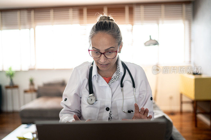 成熟的女医生在家使用笔记本电脑进行远程医疗呼叫