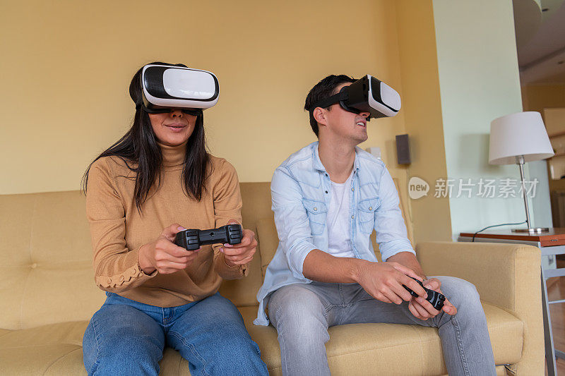 一名年轻的亚洲女子和她帅气的男友戴着VR眼镜玩3D游戏。
